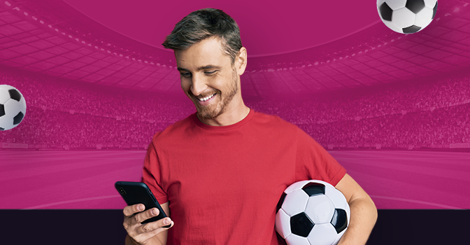 Imagem mostra homem sorrindo ao segurar uma bola e utilizar um smartphone