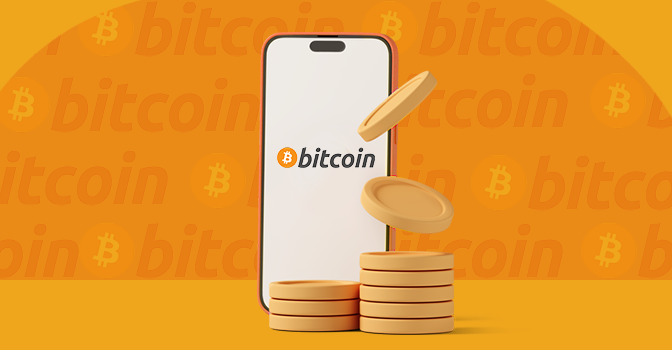 Imagem mostra uma moedas à frente de um smartphone aberto no bitcoin