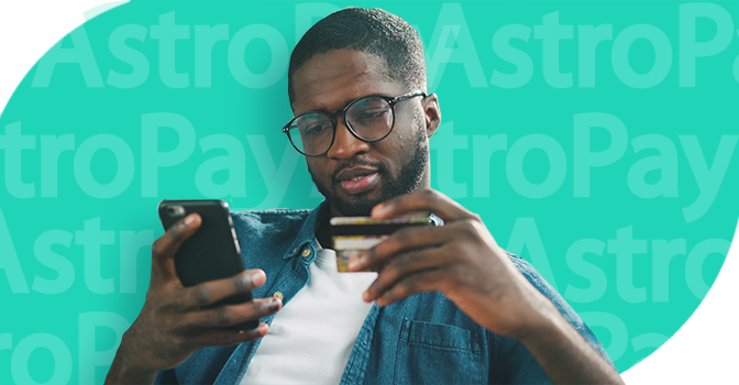 Imagem mostra um homem sorrindo segurando um smartphone e um cartão de crédito